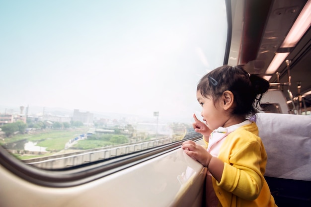 Bambini felici che viaggiano in treno. Una ragazza di due anni eccitata