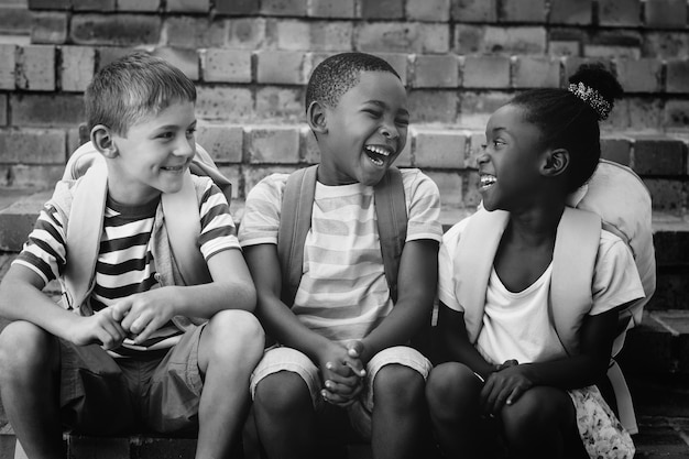 Bambini felici con gli zaini seduti sui gradini a scuola