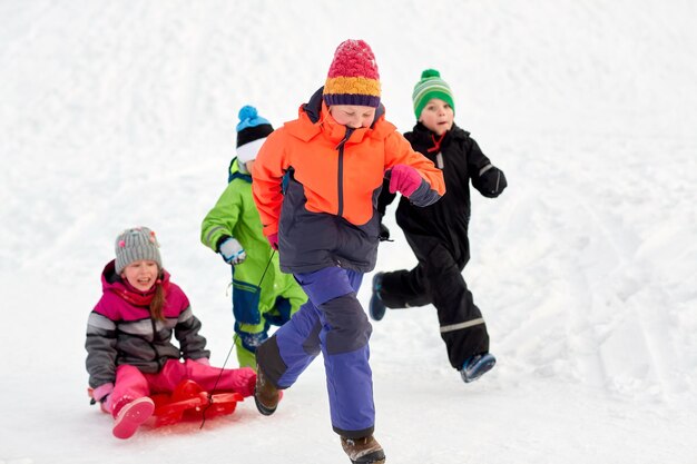 bambini felici con la slitta che si divertono all'aperto in inverno