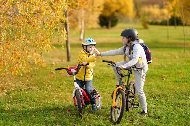 Bambini felici con le biciclette all'aperto in abiti luminosi con le bicicletteLa sorella dà il cinque al fratello