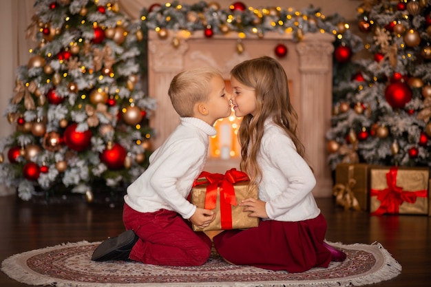 bambini felici con regalo a casa vicino all'albero di Natale e al camino