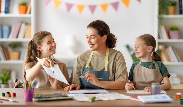 Bambini felici e insegnante a lezione di arte Donna e bambini stanno dipingendo insieme