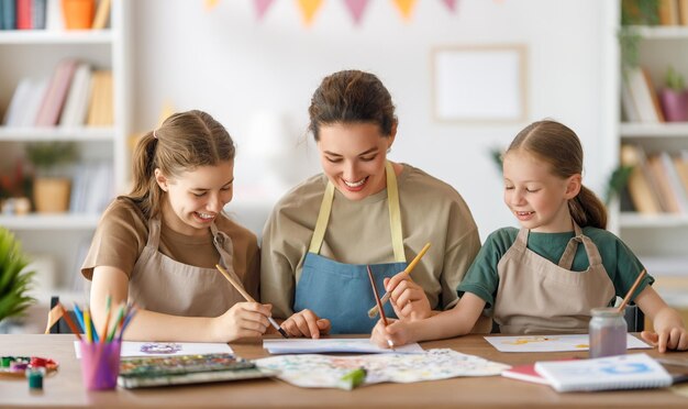 Bambini felici e insegnante a lezione di arte Donna e bambini stanno dipingendo insieme