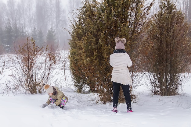 Bambini felici fanno un pupazzo di neve in un campo innevato in campagna.