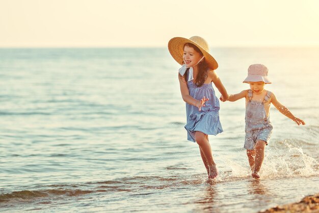 Bambini felici fratello e sorella che camminano sulla spiaggia via mare