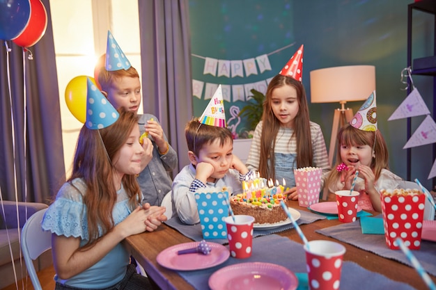 Bambini felici in cappellini per festeggiare un compleanno