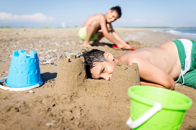 Bambini felici sulla vacanza della sabbia della spiaggia di estate divertendosi e tempo felice