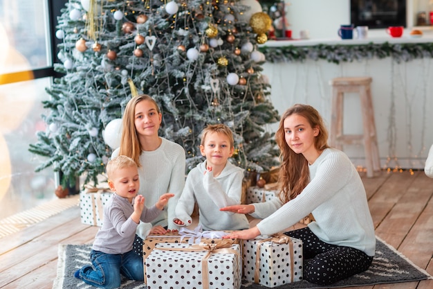 Bambini felici vicino all'albero di Natale con le scatole presenti