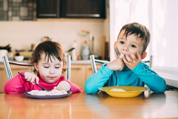 Bambini, fratello e sorella mangiano gnocchi molto carini e divertenti carini