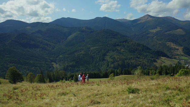 Bambini genitori contro le colline che camminano insieme ammirando il bellissimo paesaggio Famiglia bambini alla ricerca di lucci di boschi verdi di montagna che si divertono giornata estiva soleggiata vacanza Gruppo persone concetto di attività