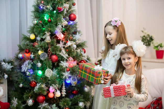 Bambini gioiosi all'albero di Natale con regali durante le vacanze di Natale
