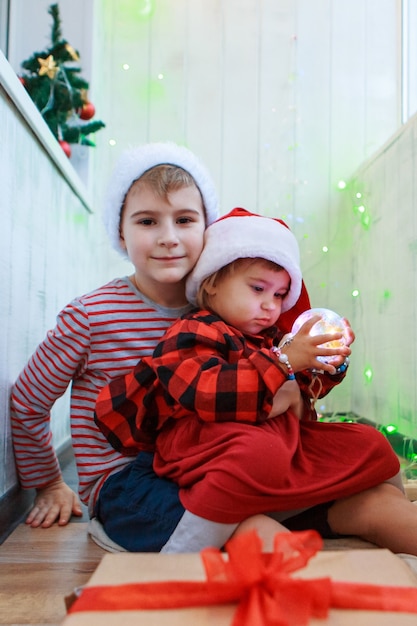 Bambini in costumi natalizi con un giocattolo dell'albero di Natale.