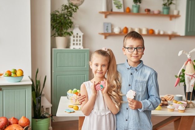 Bambini in cucina il giorno di Pasqua, ragazzo e ragazza con panpepato di Pasqua e uova