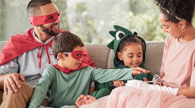 Bambini in famiglia e Halloween con bambini e genitori in costume seduti su un divano nel soggiorno della loro casa Ama l'immaginazione e la festa con un fratello e una sorella travestiti