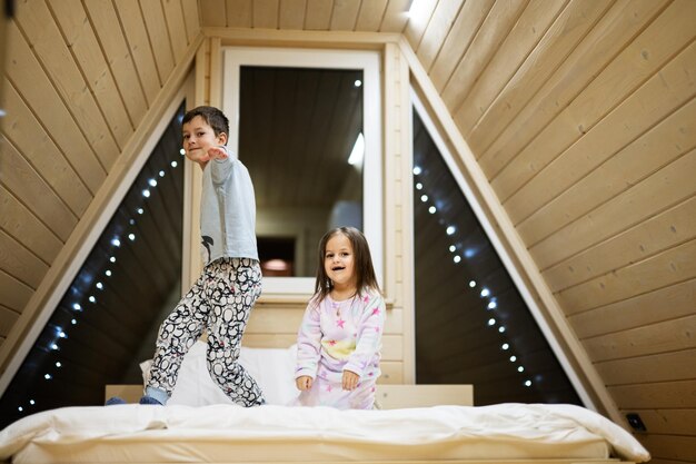 Bambini in pigiami morbidi e caldi che giocano a casa in cabina di legno Concetto di felicità per il tempo libero dell'infanzia Fratello e sorella che si divertono e giocano insieme