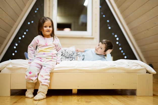 Bambini in pigiami morbidi e caldi che giocano a casa in cabina di legno Concetto di felicità per il tempo libero dell'infanzia Fratello e sorella che si divertono e giocano insieme