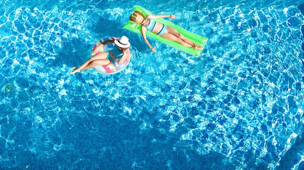 Bambini in piscina drone aereo vista dall'alto bambini felici nuotano su ciambella gonfiabile ad anello