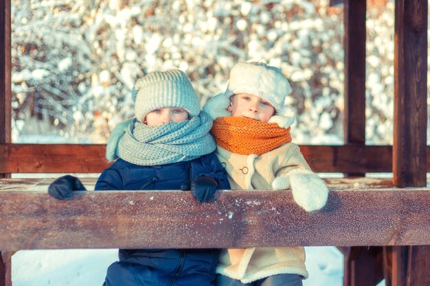 Bambini in un gazebo di legno in una foresta invernale innevata