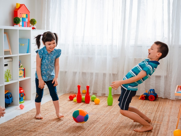 Bambini indigeni, un ragazzo e una ragazza giocano in una sala giochi per bambini, lanciando una palla