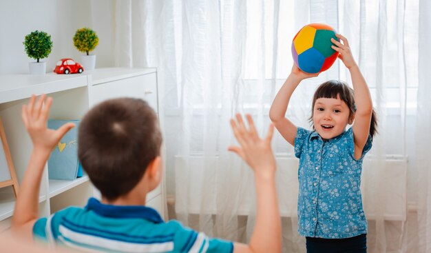 Bambini indigeni, un ragazzo e una ragazza giocano in una sala giochi per bambini, lanciando una palla.