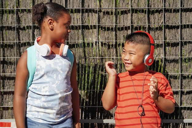 Bambini multietnici con zaini e cuffie all'ingresso della scuola