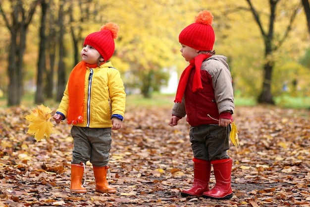 bambini nel parco autunnale con la zucca intorno alle foglie autunnali