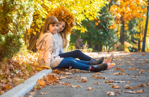 Bambini nel parco con foglie d'autunno Messa a fuoco selettiva