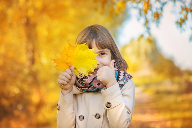 Bambini nel parco con foglie di autunno. Messa a fuoco selettiva.