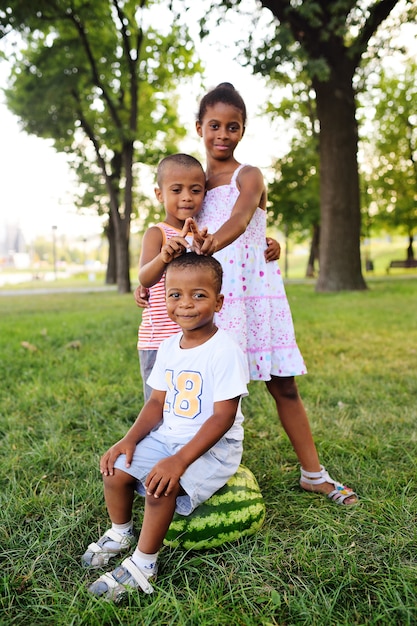 bambini neri dell&#39;afroamericano che giocano con una grande anguria nel parco sull&#39;erba e sul sorridere.