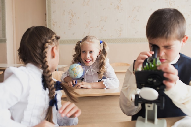 Bambini o studenti con un microscopio studiano la biologia nel laboratorio della scuola