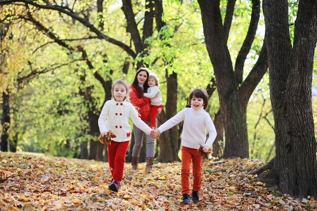 Bambini per una passeggiata nel parco autunnale. Caduta delle foglie nel parco. Famiglia. Autunno. Felicità.