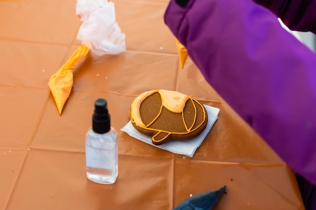 Bambini piccoli a una festa di Halloween. La bambina decora i biscotti per Halloween