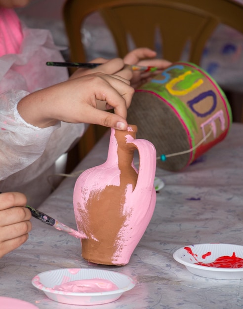 Bambini piccoli che decorano ceramiche di argilla fatte a mano