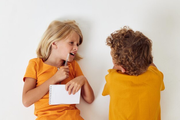 Bambini piccoli che disegnano quaderni sdraiati sul pavimento sfondo chiaro inalterato