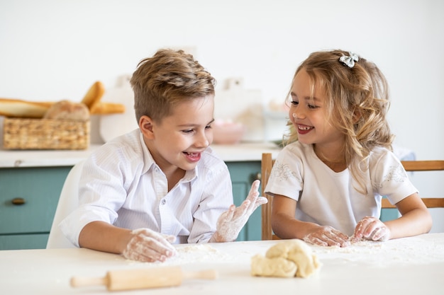 Bambini piccoli che giocano mentre cucinando insieme i biscotti in cucina