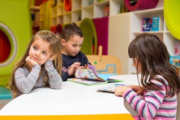 Bambini piccoli che leggono e imparano nella scuola materna