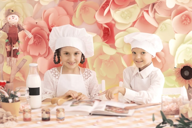 Bambini piccoli felici in forma di chef per cucinare deliziosi piatti in cucina