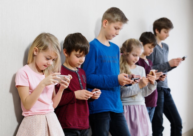 Bambini positivi che usano i loro telefoni cellulari