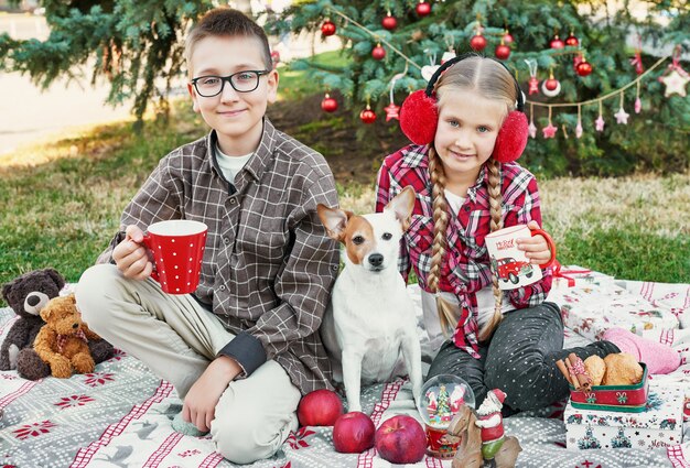 bambini ragazzo e ragazza con un cane Jack Russell Terrier vicino a un albero di Natale con regali,