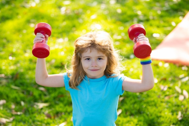 Bambini sani vita e concetto di sport Ritratto di bambino ragazzo che lavora con manubri all'aperto motiva