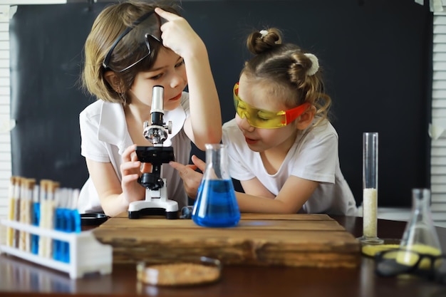 Bambini scienziati Gli scolari in laboratorio conducono esperimenti Ragazzo e ragazza esperimenti con un microscopio