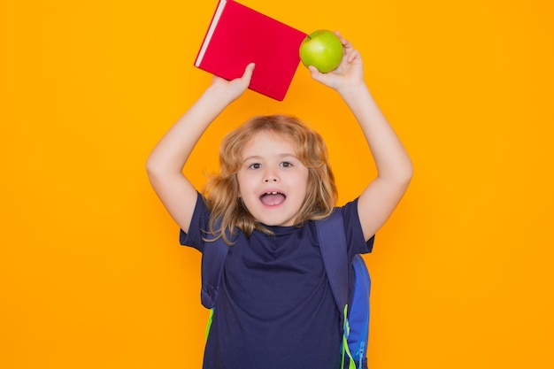 Bambini scolari di scuola elementare con libro e mela isolati su sfondo giallo