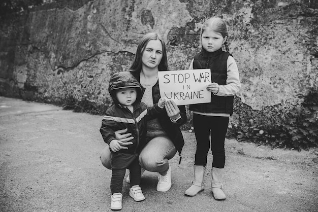 Bambini sconvolti con madre che protestano guerra conflitto solleva banner con iscrizione testo messaggio Fermare la guerra in Ucraina Crisi pace fermare l'aggressione russa bambino contro la guerra Nessuna guerra Foto in bianco e nero