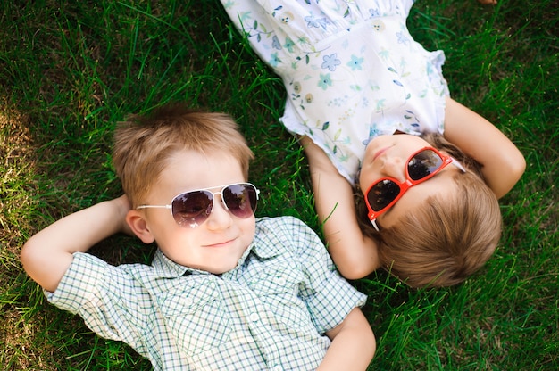 Bambini sorridenti al giardino in occhiali da sole