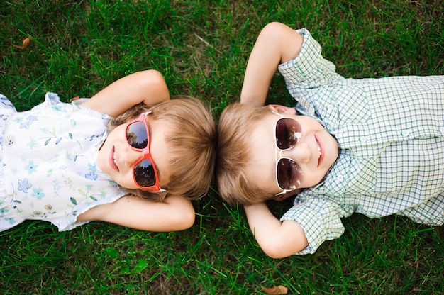 Bambini sorridenti al giardino in occhiali da sole