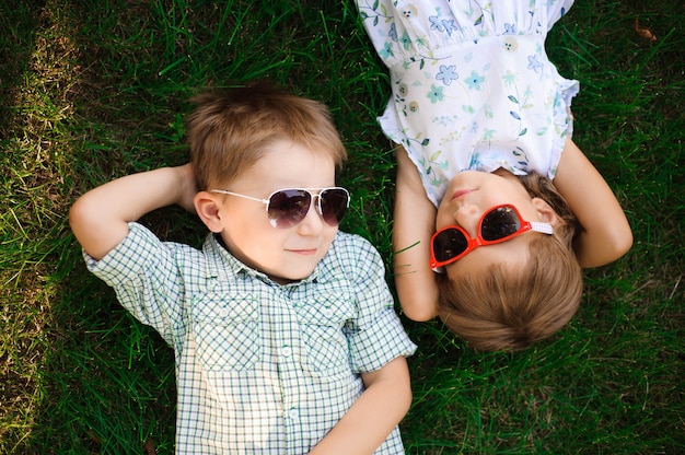 Bambini sorridenti al giardino in occhiali da sole