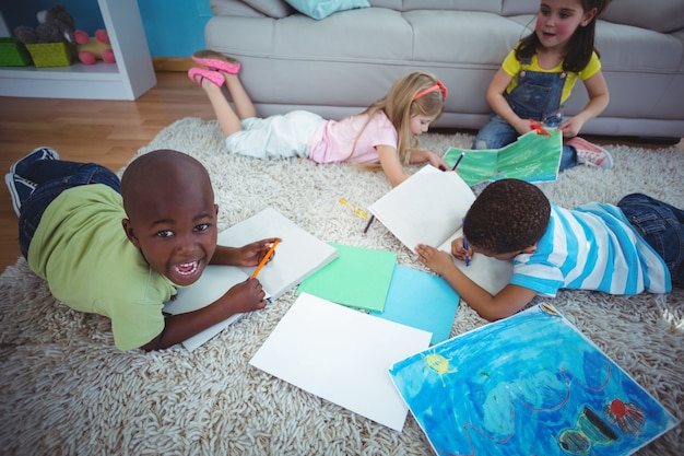 Bambini sorridenti che disegnano le immagini su carta