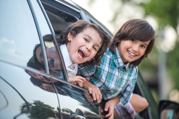 Bambini sorridenti che guardano attraverso il finestrino della macchina