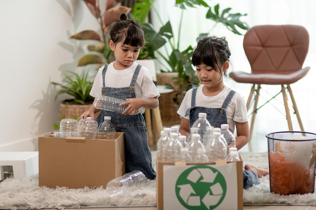 Bambini sorridenti che si divertono a separare bottiglie di plastica e carta in un cestino