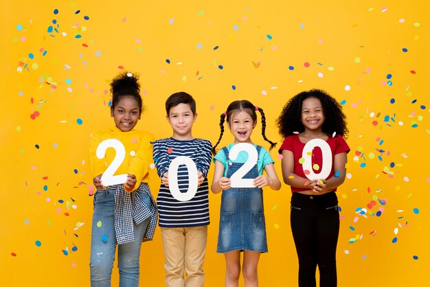 Bambini sorridenti svegli della corsa mista che mostrano i numeri 2020 che celebra il nuovo anno